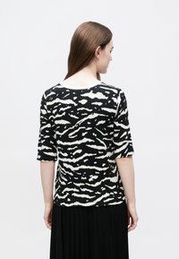 Mustvalge triibuline top ümmarguse kaelusega, kolmeveerandvarrukatega ja lõdva lõikega, valmistatud kergest kangast.