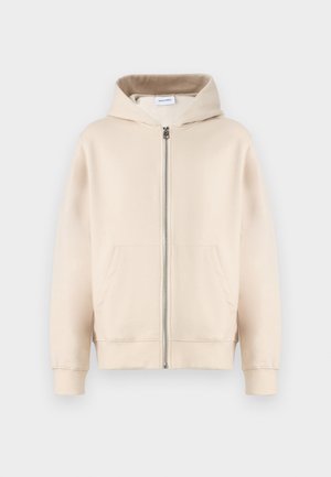 Bež kapuča s punim zipom, dvema sprednjima žepoma, rebrastimi manšetami in robom. Izdelana iz mehkega, udobnega materiala.