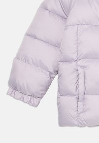 Light purple puffer jacket sleeve with visible quilted pattern. Features a gathered cuff and side pocket detail, made from smooth, synthetic material.