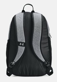 Mochila negra con correas grises, hecha de un tejido duradero. Cuenta con correas ajustables, un asa en la parte superior y un acento con el logo de Under Armour.