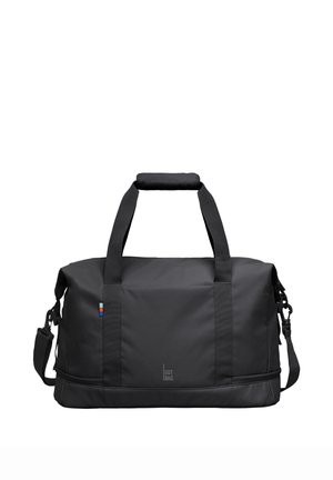 Schwarze rechteckige Duffel-Tasche mit zwei Griffen, einem gepolsterten Schulterriemen, kleinem farbigem Etikett und "GOT BAG" Logo vorne in der Mitte.