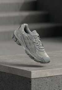 Gai pelēks sporta apavi ar teksturētu, gludu virsmu. Ievērojama sieta dizaina, auklu aizdare un mīksts zole atbalstam.