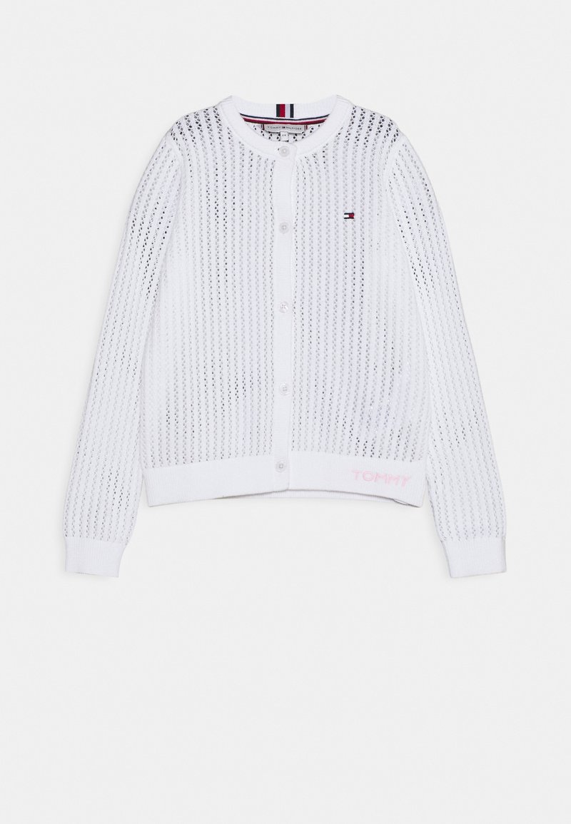 Cárdigan de botón de manga larga de punto abierto en blanco, con puños acanalados, escote redondo, pequeño logo de Tommy Hilfiger en el pecho y texto "TOMMY" cerca del dobladillo.