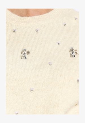 Cream knit sweater with small pearl and rhinestone clusters scattered across the fabric near the neckline.