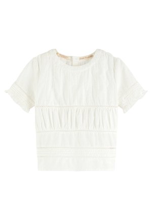 Hvid top med korte ærmer og rund halsudskæring, med lodrette plisseringer og detaljer ved det indsnørede talje. Let bomuldsstof med blonder.