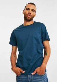 Mørkeblå kortærmet t-shirt med rund halsudskæring, lavet af glat stof, parret med lyseblå denimjeans.