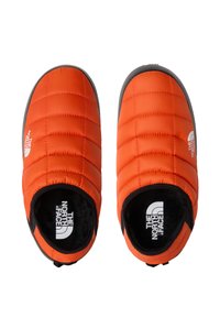 Scarpe slip-on arancioni isolate con texture trapuntata e interno nero, dotate di suola in gomma grigia e logo del marchio sul lato.