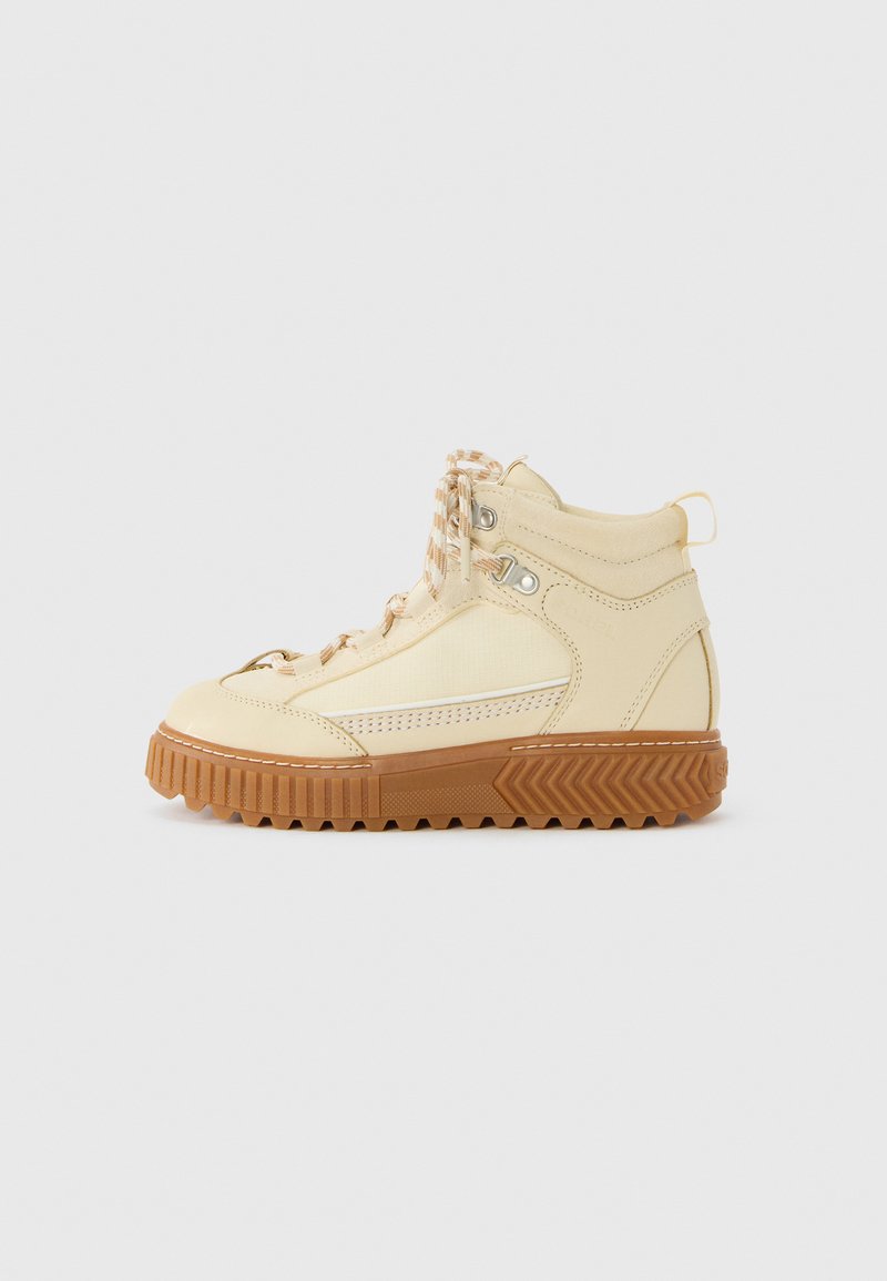 Beige høyhælte sneakers med stripete lisser og tykk brun rillet såle, vist fra siden på en enkel hvit bakgrunn.