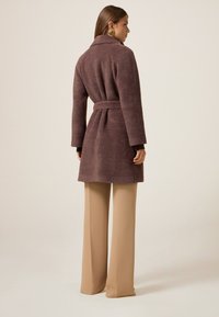 Bruine textuurcoat met een riem, voorzien van een kraag en lange mouwen, gecombineerd met tan hoge taille broek.