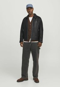 Black leather jacket, brown cardigan, white shirt, gray jeans, blue cap, brown boots; features simple design and neutral colors.