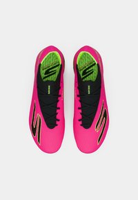 Svijetlo ružičaste atletske tenisice s teksturiranom površinom, crnim akcentima i zelenom uzorkovanom uloškom, s elegantnim dizajnom i crnim vezicama.