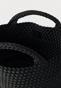 Μαύρο υφαντό καλάθι αποθήκευσης με δύο στρογγυλές λαβές. Διαθέτει υφή στην επιφάνεια και μικρό λογότυπο στην εσωτερική πλευρά.