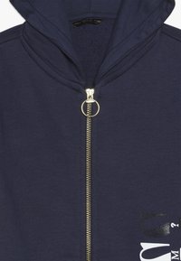 Marine blauwe zip-up hoodie met een gouden rits, voorzien van een gladde textuur en een grafische print in het wit. Inclusief een capuchon en ribgebreide accenten.