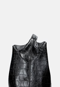 Sac en cuir noir avec un motif de crocodile texturé, présentant une forme décontractée et une fermeture éclair sur le dessus.
