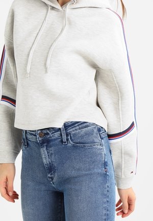 Lysegrå cropped hoodie med røde, hvide og blå striber på ærmerne, båret med højtaljede blå denimjeans.