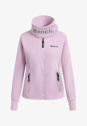 Lichtpaarse zip-up jas met een hoge kraag. Bevat zwarte hardware en branding op de kraag en borst. Zacht materiaal met een gladde textuur.