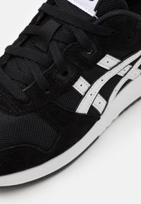 Czarne trampki wykonane z połączenia zamszu i siateczki. Charakterystyczne białe paski i czarne sznurówki. Gumowa podeszwa z fakturowanym wzorem.