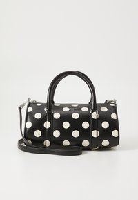 Black leather handbag featuring large white polka dots, dual top handles, and a detachable shoulder strap for versatile carrying options.
