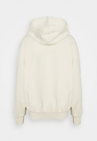 Felpa color crema con un ampio cappuccio, polsini e orlo a coste. Il tessuto appare liscio e ha una vestibilità rilassata, con giunture minime visibili.