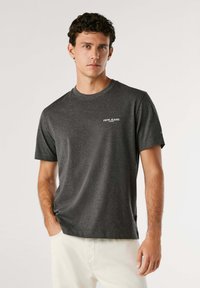Grijze T-shirt met korte mouwen, gemaakt van zachte katoen, met het logo "PEPE JEANS" in het wit op de linkerkant van de borst. Rechte zoom en een ronde halsontwerp.