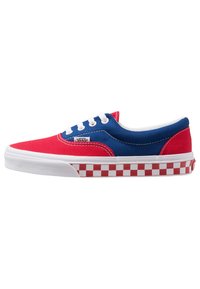 Rode en blauwe canvas sneakers met witte veters, voorzien van een rood en wit geblokt patroon op de zool. Afgeronde neus en een laag profiel ontwerp.