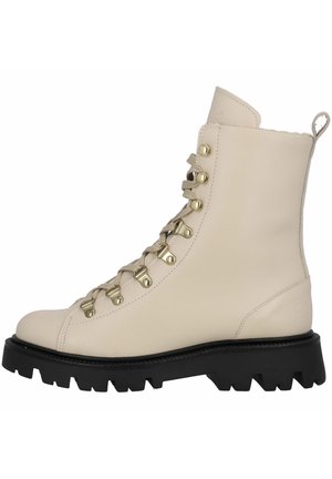 Beige læderankelstøvle med sort chunky rillesål, guldfarvede snørehuller, beige snørebånd og trækflig bagpå.