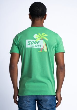 Zelené bavlněné tričko s grafikou na zádech, která zobrazuje palmou, surfařský prkno a text "SURF RIDERS" v tučném písmu. Krátké rukávy, volný střih.
