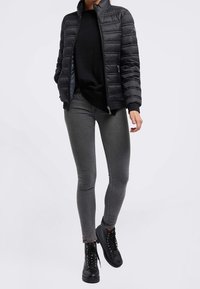 Czarna pikowana kurtka z wysokim kołnierzem, noszona na czarnej bluzce. Dopełnieniem stroju są dopasowane szare dżinsy i czarne botki na sznurowadła.