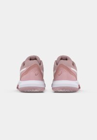Světle růžové sportovní boty s texturovaným svrškem, bílými detaily a gumovou podrážkou. Na zadní části se nachází specifický vzor a značka.
