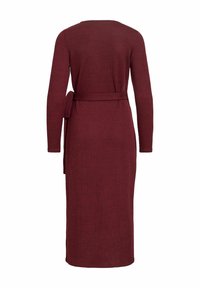 Robe rouge bordeaux en maille à manches longues avec une taille ceinturée, une silhouette droite, un col rond et une texture lisse. Aucun motif ni ornement visible.