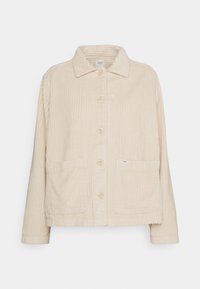 Beige corduroy jasje met lange mouwen, knoopsluiting, twee voorzakken en een textuurlijke kraag. Merkenlabel zichtbaar op de zak.