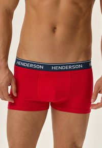 Czerwone męskie bokserki wykonane z miękkiego materiału, z czarnym pasem w talii, na którym powtórzone białymi literami słowo "HENDERSON" z przodu.