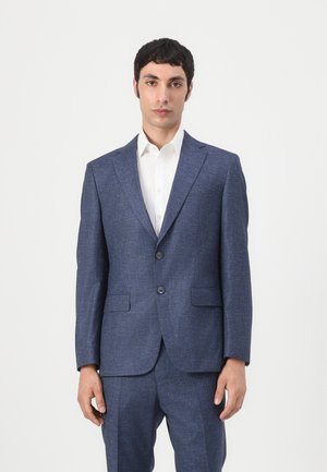 Abito blu navy su misura realizzato in tessuto testurizzato, caratterizzato da un frontale con due bottoni, revers a lancia e tasche frontali, abbinato a una camicia bianca.
