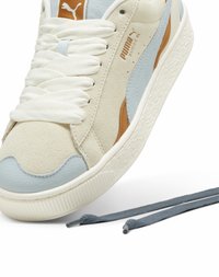 Puma suède sneakers met een crèmekleurige bovenkant, lichtblauwe accenten en bruine details. Voorzien van dikke witte veters en een getextureerde rubberen zool.