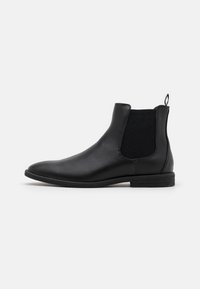 Bottes cheville en cuir noir avec panneaux élastiques latéraux et un dos texturé, dotées d'un bout arrondi et d'un talon plat bas.