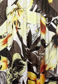 Tkanina z abstrakcyjnym kwiatowym wzorem w odcieniach żółci, brązu, czerni i pomarańczy, z dużymi płatkami i kształtami liści.