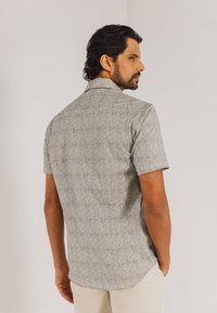 Korte mouwen, lichtgrijs shirt met een subtiel bloemenpatroon, voorzien van een standaard kraag en een rechte zoom, gemaakt van een lichte stof.