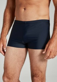 Marineblaue Badehose aus dehnbarem Material, mit einem schlichten Design, enganliegendem Schnitt und glatter Oberfläche. Keine sichtbaren Muster oder Beschläge.