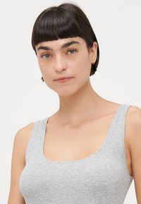 Graues, geripptes Tanktop mit breiten Trägern und rundem Ausschnitt, das eine weiche Textur und eine figurbetonte Passform zeigt.