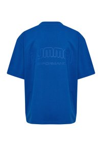 Blå bomulls T-shirt med avslappnad passform, med en texturerad logotyp "HUMMEL PERFORMANCE" subtilt prägling på baksidan. Korta ärmar.