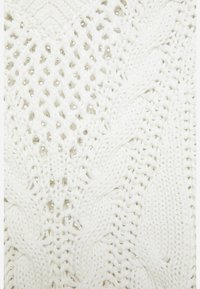 Biała dziana tkanina z teksturowanym wzorem zawierającym motywy diamentowe i warkoczowe, z małymi otwartymi częściami w splocie na całej powierzchni.