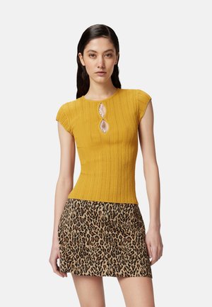 Top giallo a righe con maniche corte e dettaglio a chiave, abbinato a una mini gonna a stampa leopardata con silhouette aderente e texture morbida.