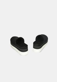 Pantofi platform negri, slip-on, cu o finisare mată netedă și talpă mare din cauciuc alb. Au un vârf rotund deschis și o talpă interioară căptușită.