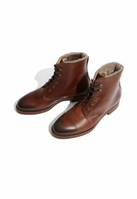 Botas de cuero marrón hasta el tobillo, con un cuerpo texturizado, puntera suave, sistema de cordones y suave forro de piel en la parte superior.