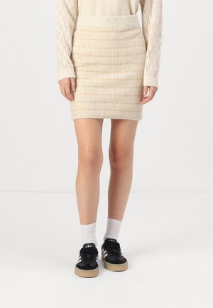 Beige niitküpsiste koos tekstuuriga mustriga. Kõrge vöökoht, kitsenev lõige. Kandmisel mustad tossud ja valged pahklu socksid.