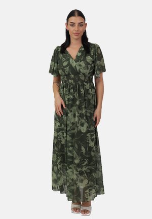 Robe maxi florale verte avec un design à enveloppe, des manches courtes et flottantes, et une taille smockée, fabriquée en tissu léger et transparent.