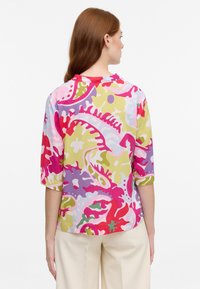 Blusa colorata con un motivo floreale in tonalità di rosa, viola, verde e giallo, con una vestibilità comoda e maniche a tre quarti.