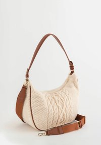 Bolso de hombro de punto color crema con patrón de cable, detalles en cuero marrón, correa ajustable y herrajes en tono dorado. Textura suave y forma redondeada.