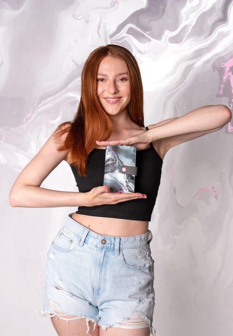 Marble-patterned phone case in gray, black, and pink, featuring a magnetic closure and rounded edges, held between hands against a soft backdrop.