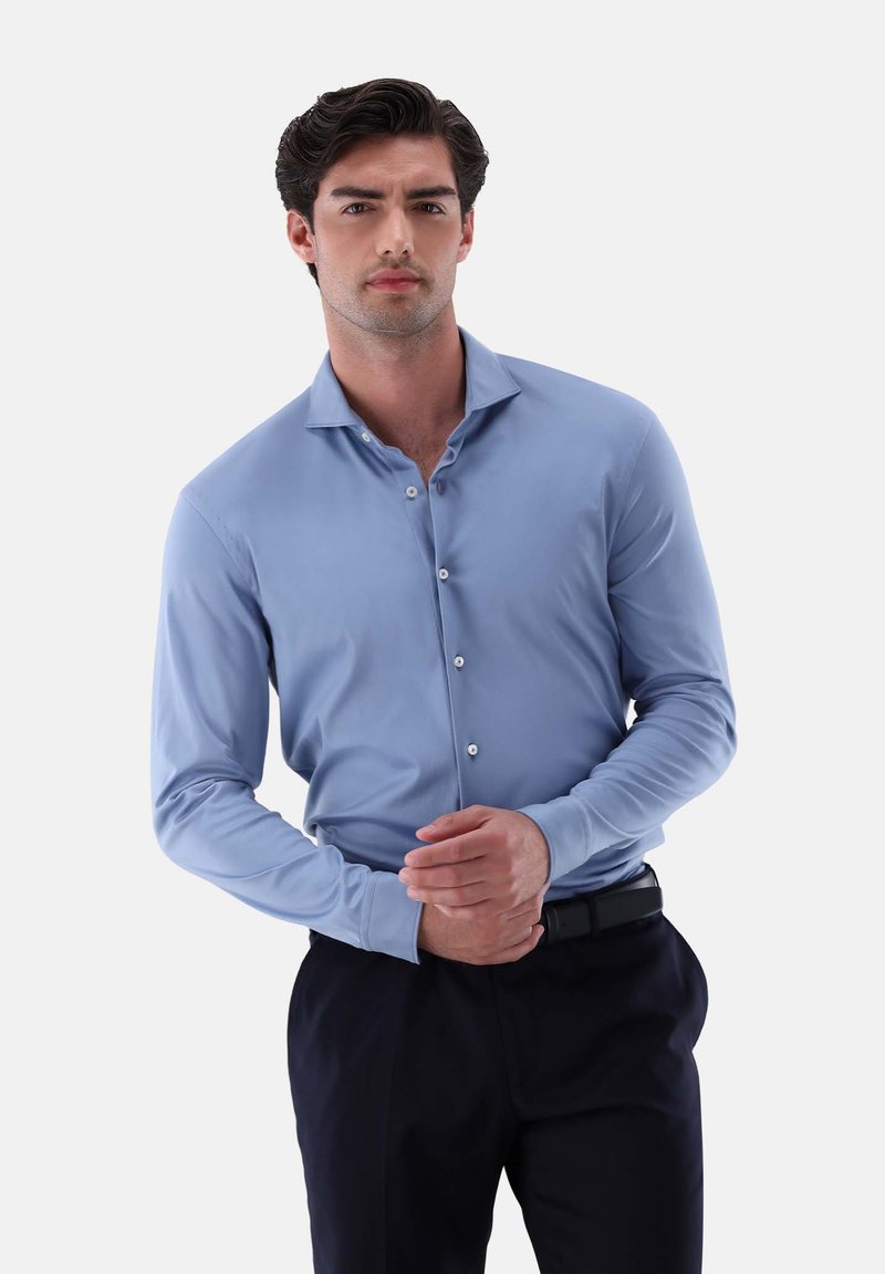 Himmelblaues Langarmhemd mit Button-Down-Kragen, ausgestattet mit weißen Knöpfen, glatter Textur und kombiniert mit dunklen Hosen und einem schwarzen Gürtel.